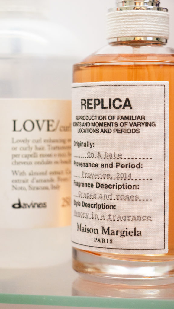 Maison Margiela Parfüm und Davines Haarspray auf einem Glasgestell arrangiert.