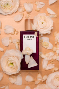 Loewe Earth Parfüm auf Blumen arrangiert.